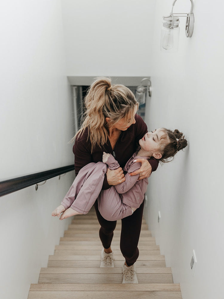 Shannon carrying her daughter up the stairs in her workout clothes