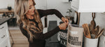 Shannon Willardson in kitchen making protein shakes with all that nutrition whey powder chocolate peanut butter chocolate and vanilla fitness mother mom