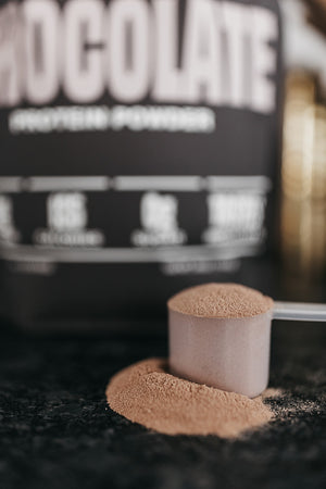 A scoop of chocolate protein powder on the counter