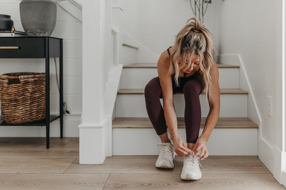 Woman tying shoes on stairs in workout clothes