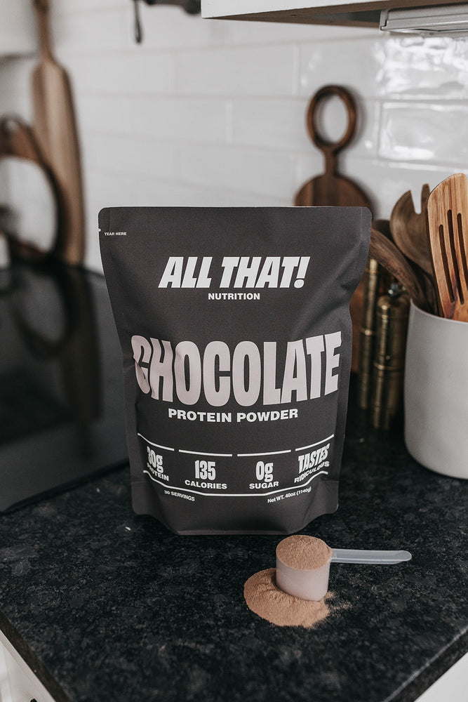 Chocolate protein powder bag on the counter with a scoop of protein in front of it