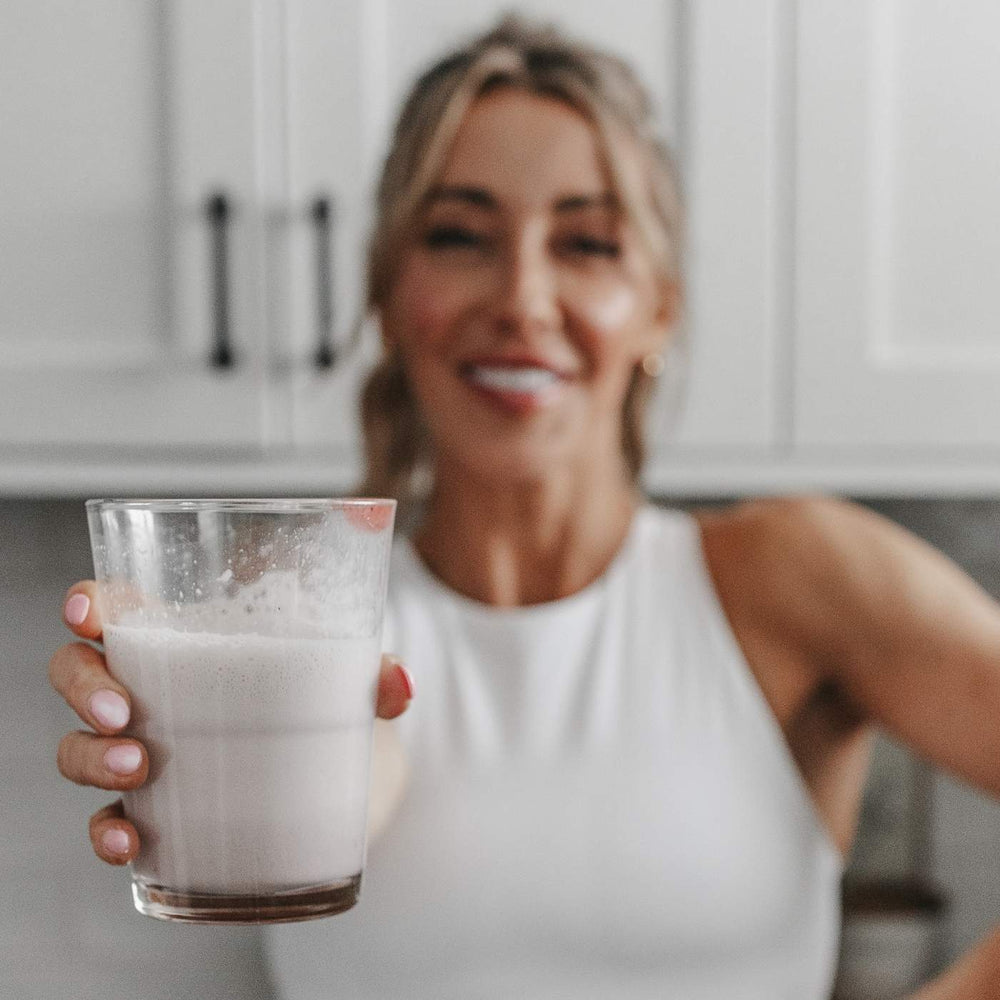 Shannon Willardson in kitchen making protein shakes with all that nutrition whey powder chocolate peanut butter chocolate and vanilla fitness mother mom